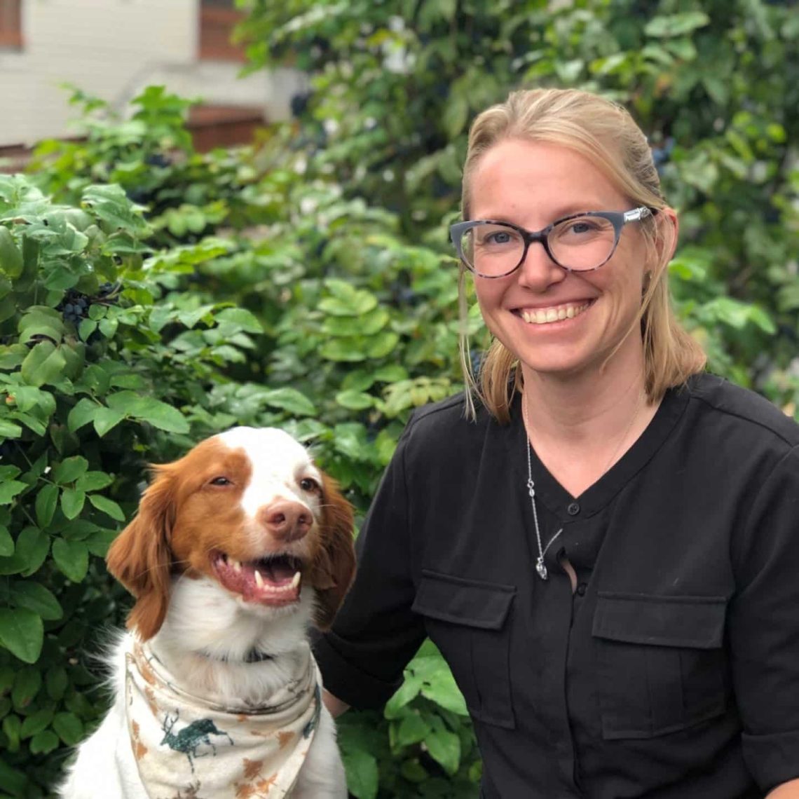 Dr. Krystal Harris, DVM, MS, DACVIM, Board-Certified Oncologist at Boundary Bay Veterinary Specialty Hospital, smiling outdoors beside a happy dog wearing a bandana.